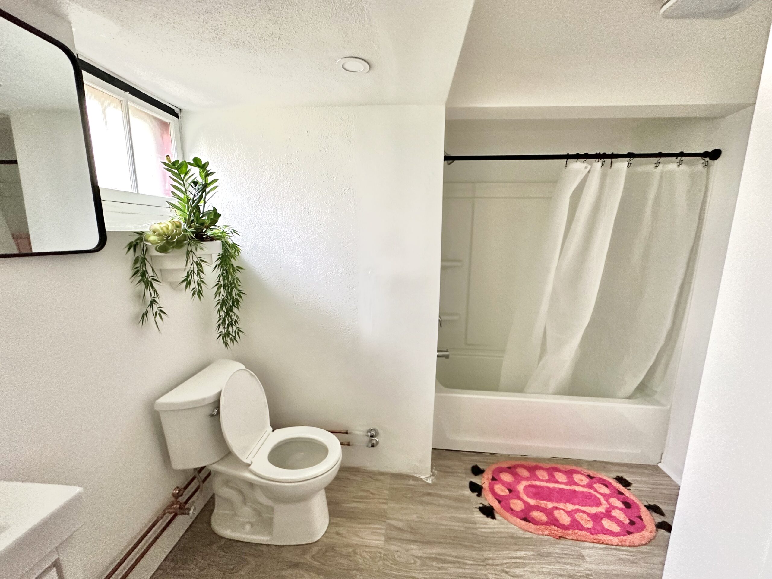 Renovated white bathroom with tub, shower curtain, and new floor