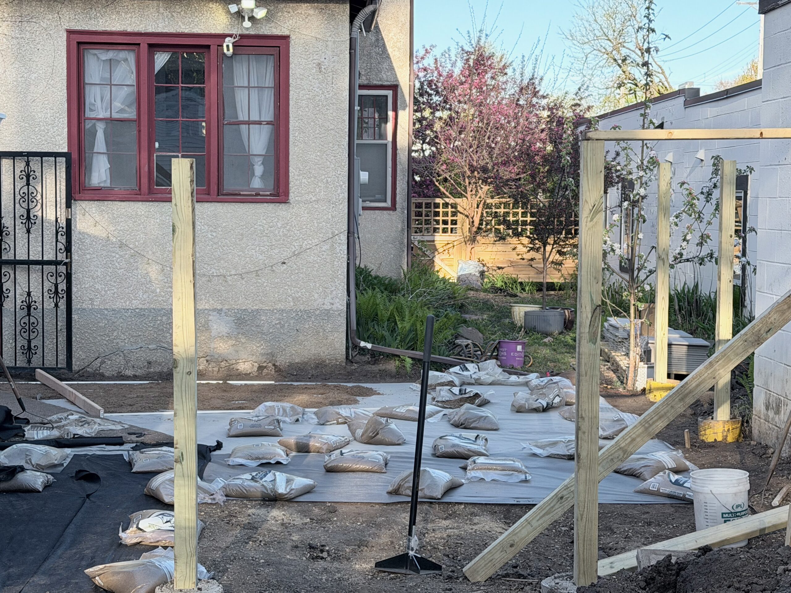 Fence posts set in the yard with bags of base material staged on the ground