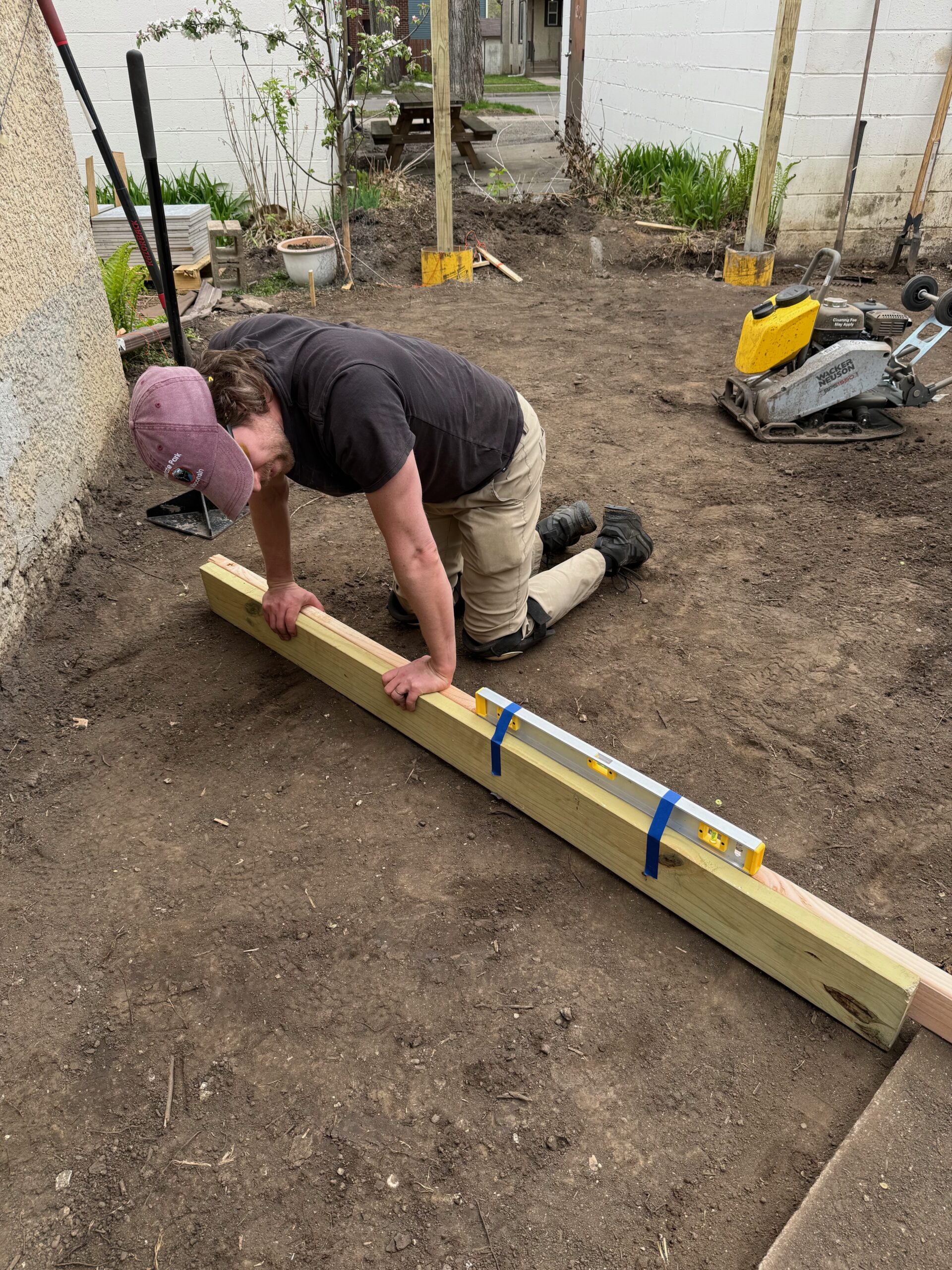 Kneeling in the backyard to level a fence beam