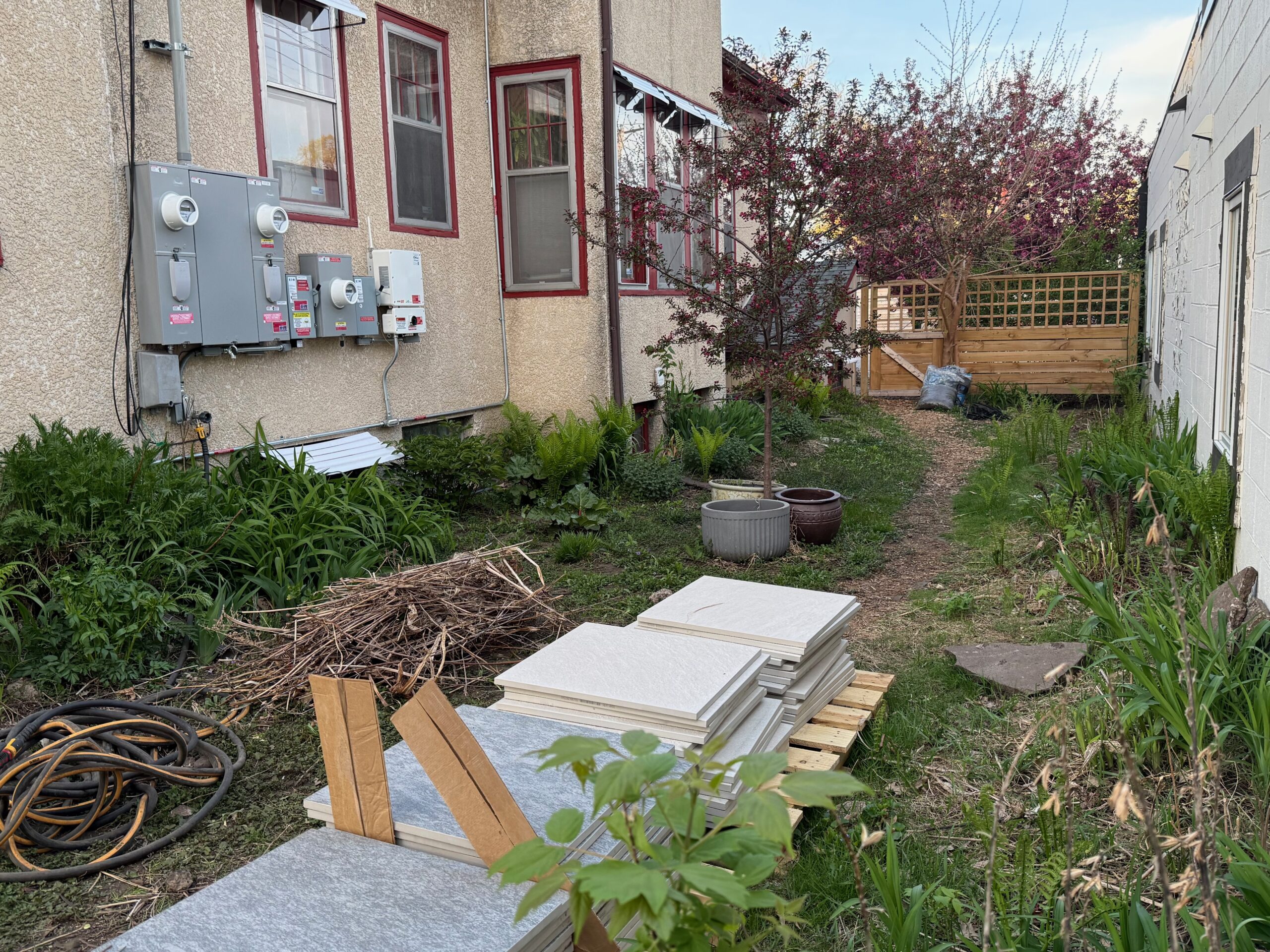 Side yard of the duplex with separate electrical meters and conduit on the wall