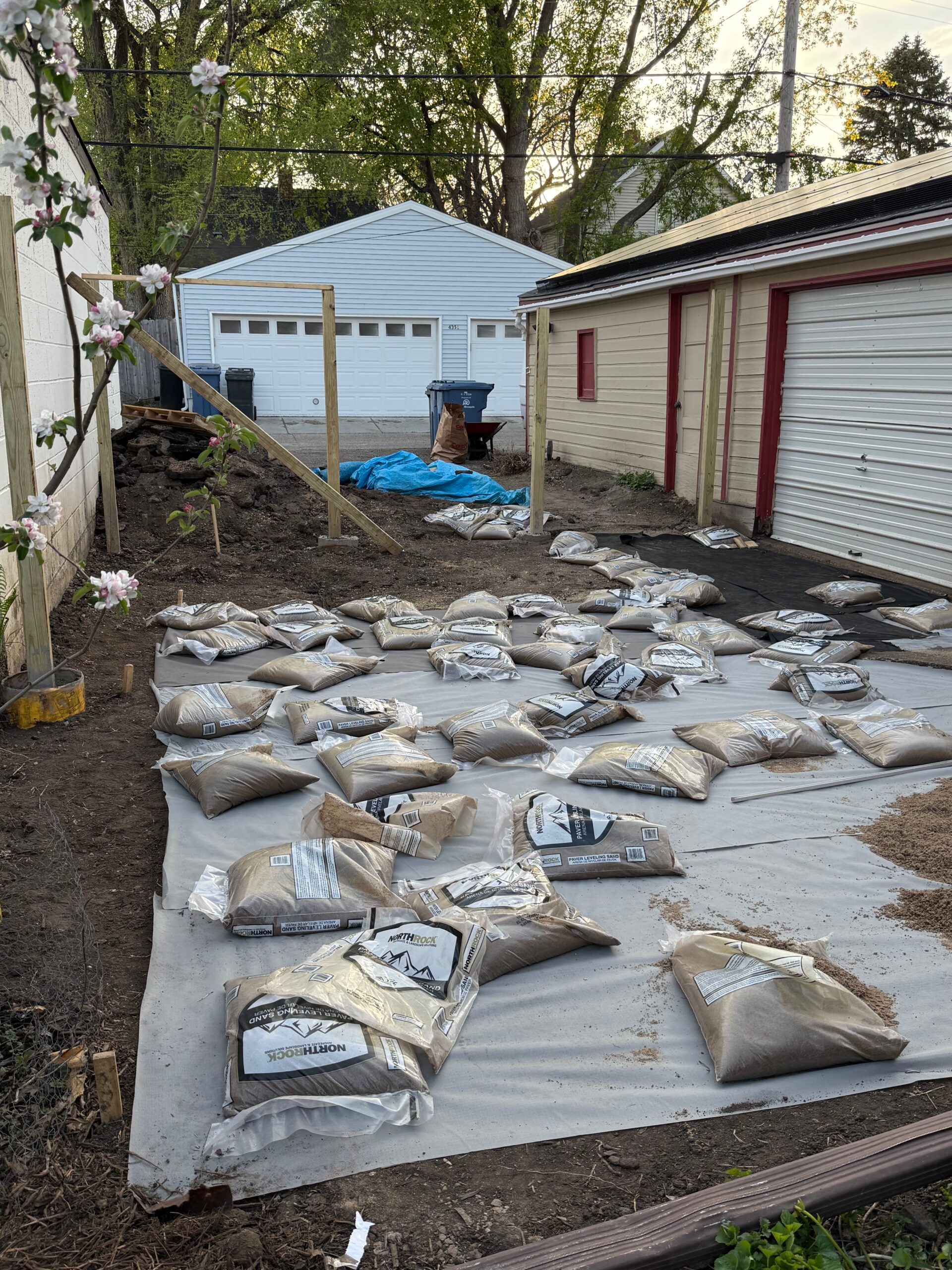 Bags of paver base laid out in rows on landscape fabric