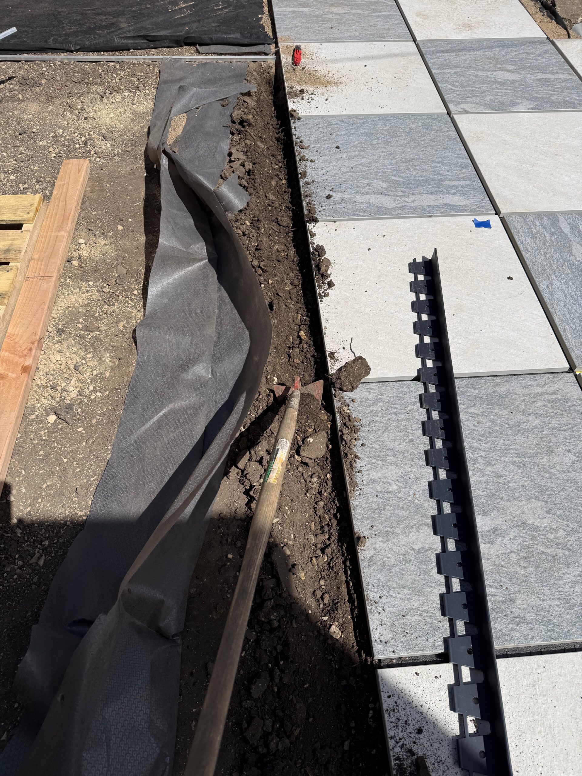 Landscape fabric and black edging installed beside pavers
