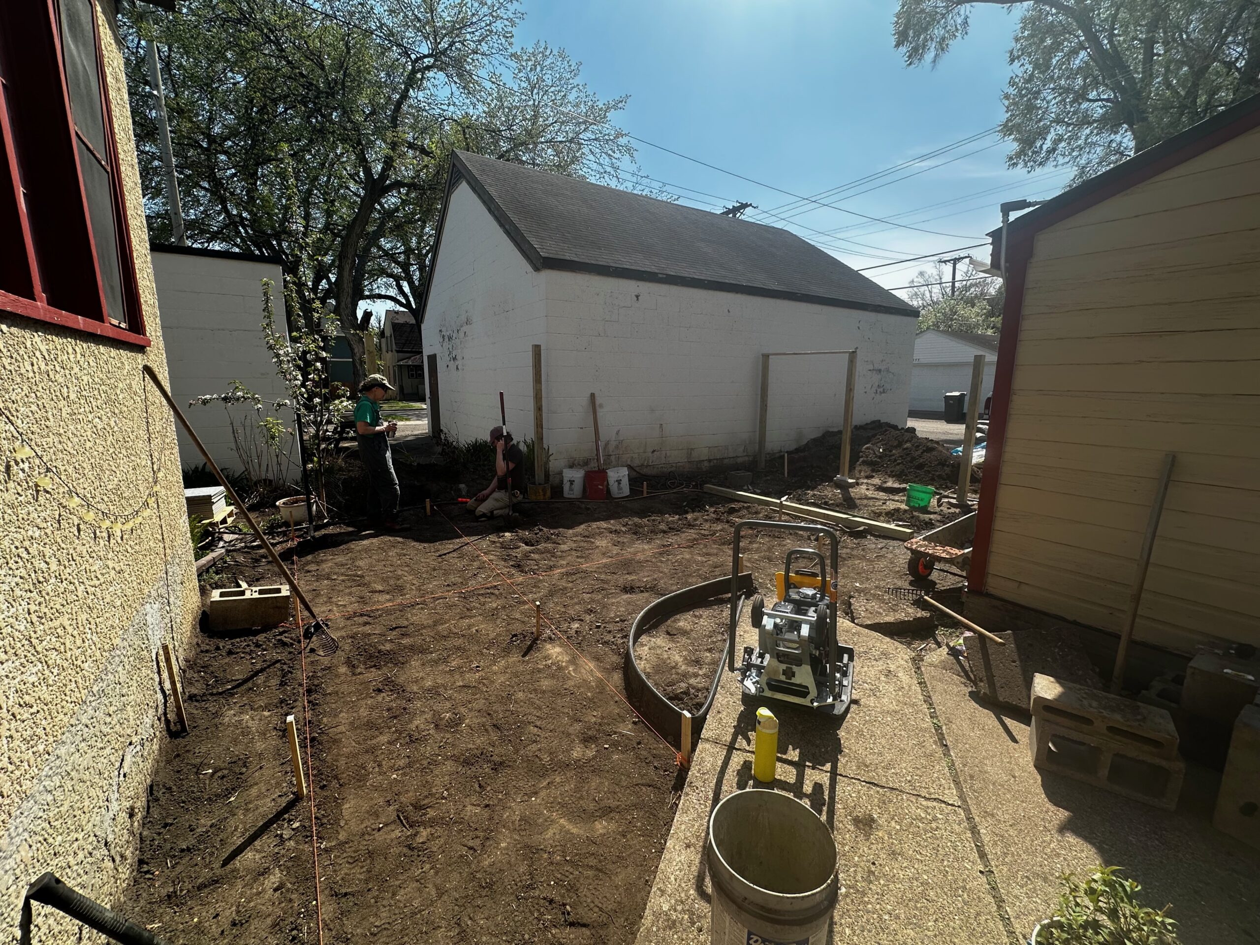 Bare dirt backyard with a plate compactor during ground preparation