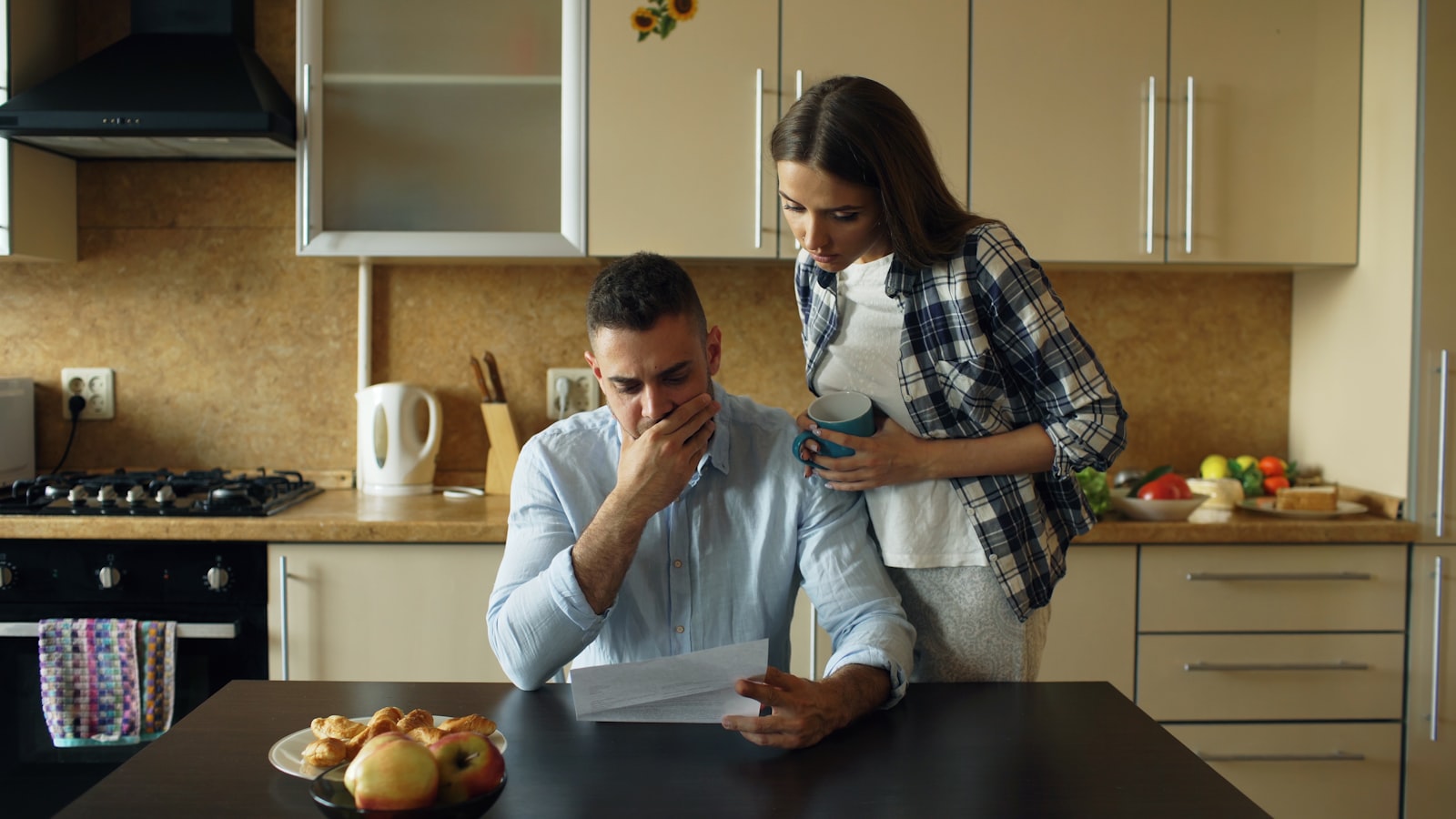 Two people at a kitchen table working through monthly housing costs on paper