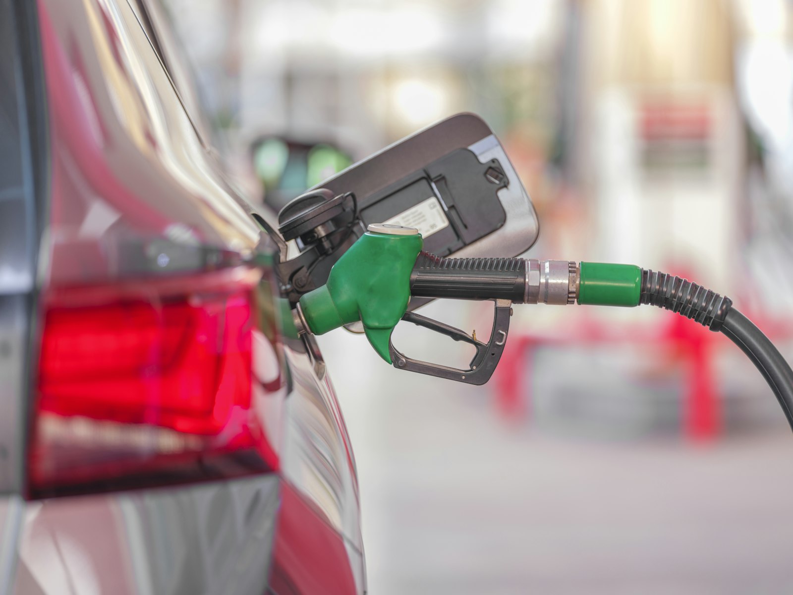 A fuel pump nozzle connected to a car at a gas station