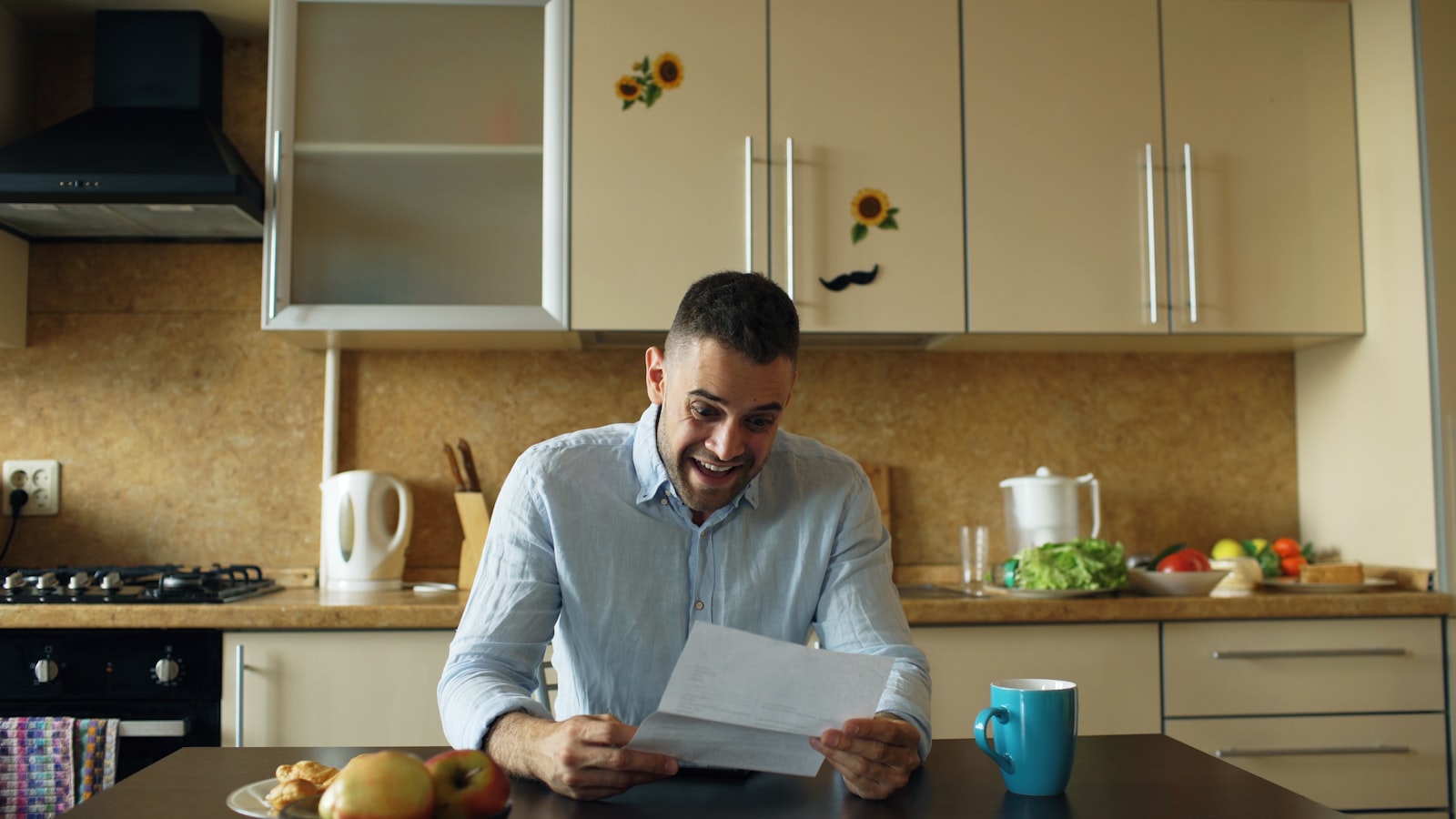 A person reading a letter and paperwork at a kitchen table