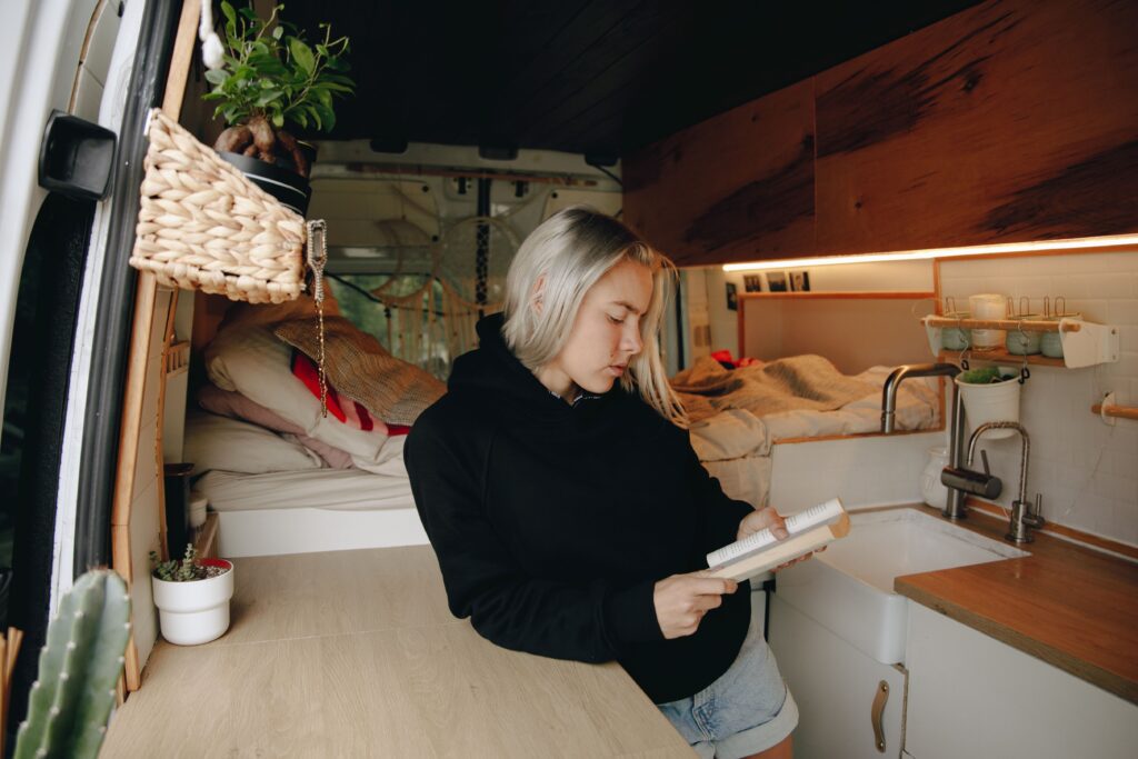 Stock photo of a person sitting and working at a small desk inside a van conversion