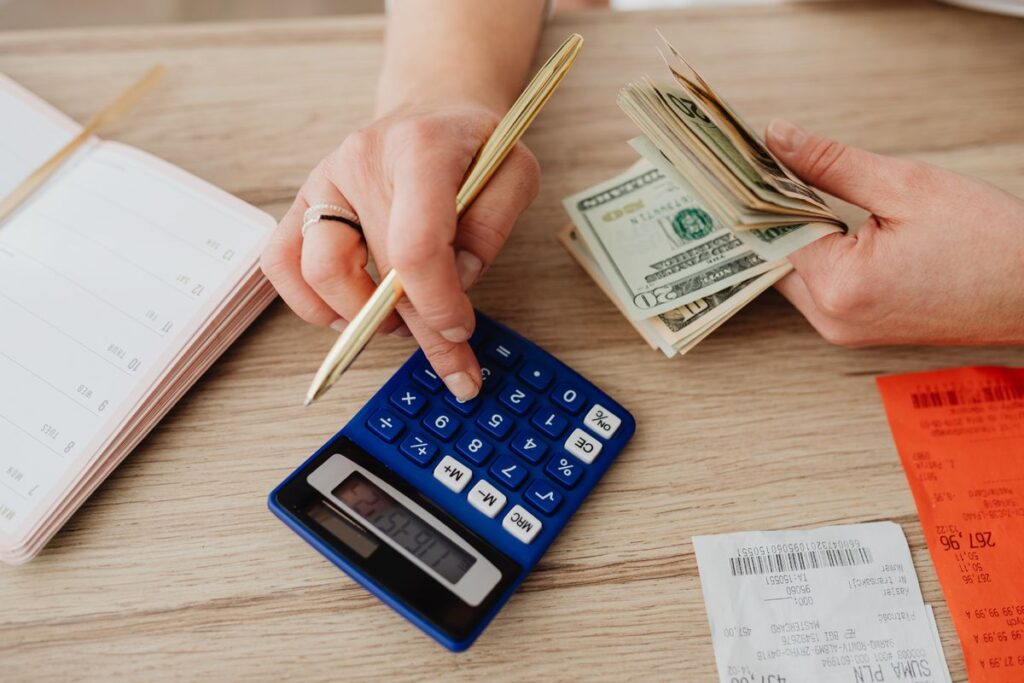 Cash and a calculator on a table next to a notepad