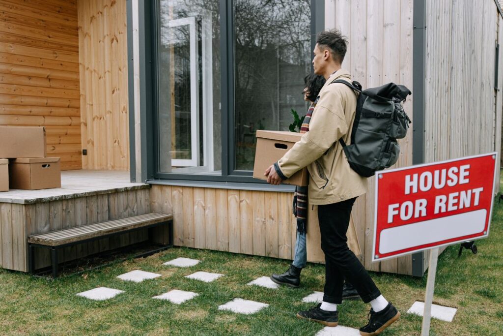 Stock photo of a couple carrying boxes into a rental home