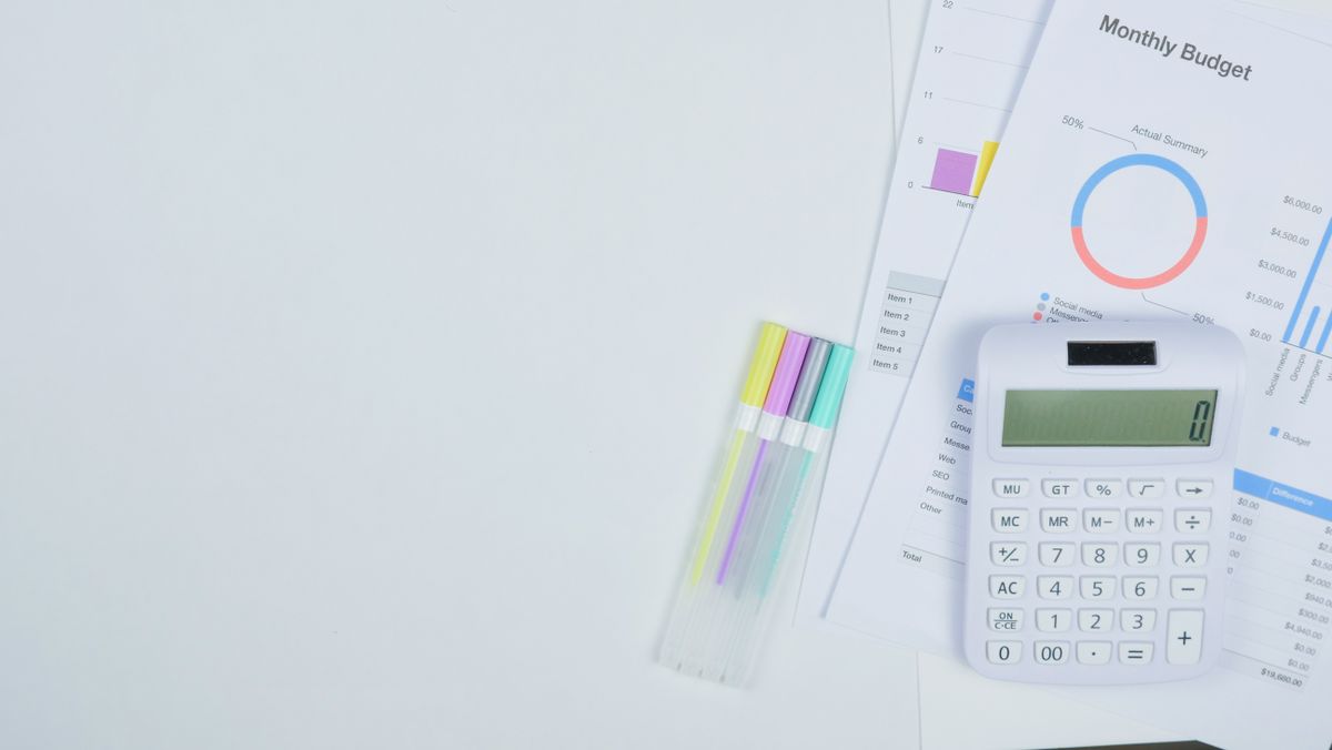 A desk with a notebook and pen where household budget figures are worked out by hand
