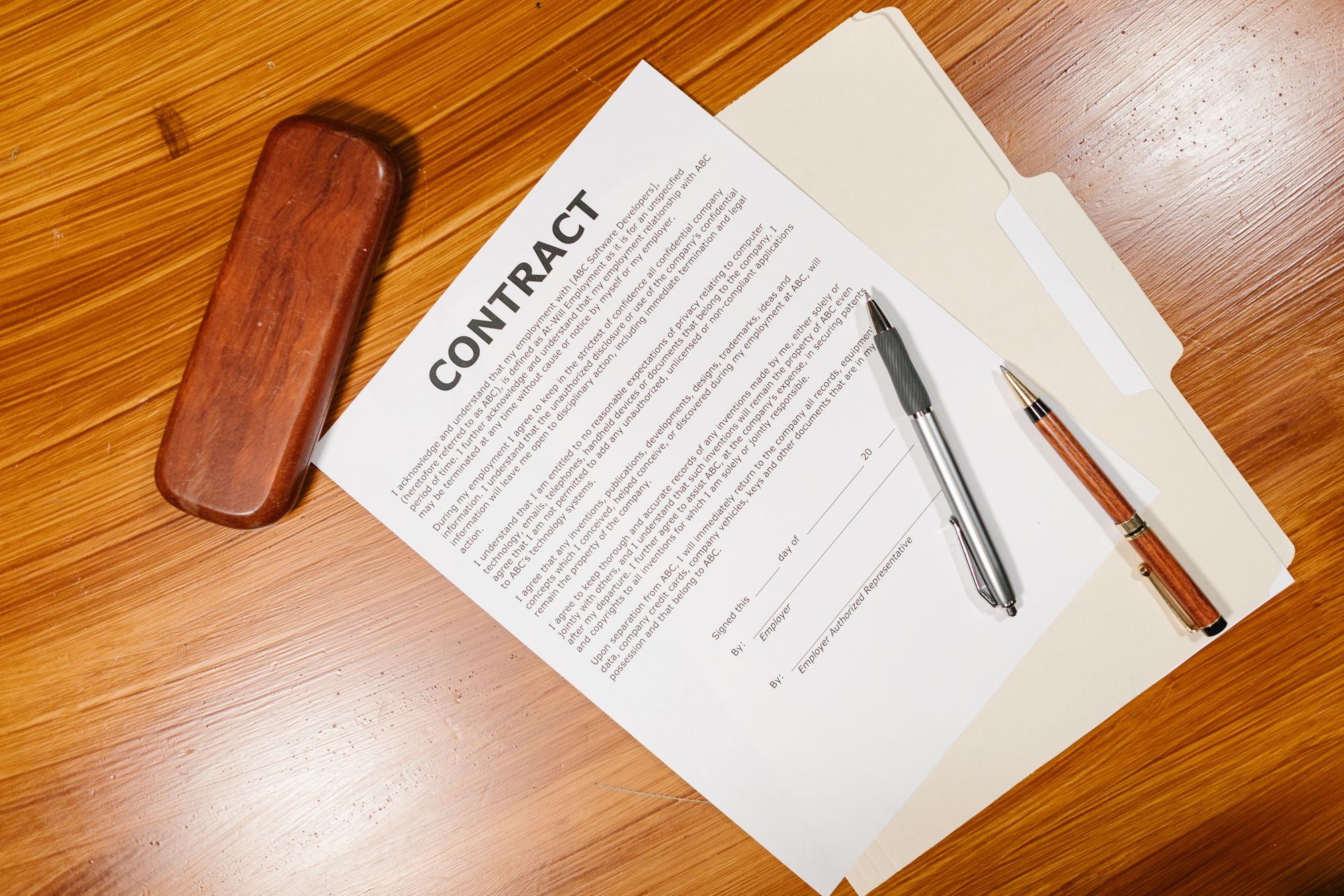 A printed contract with a pen and stamp on a wooden desk
