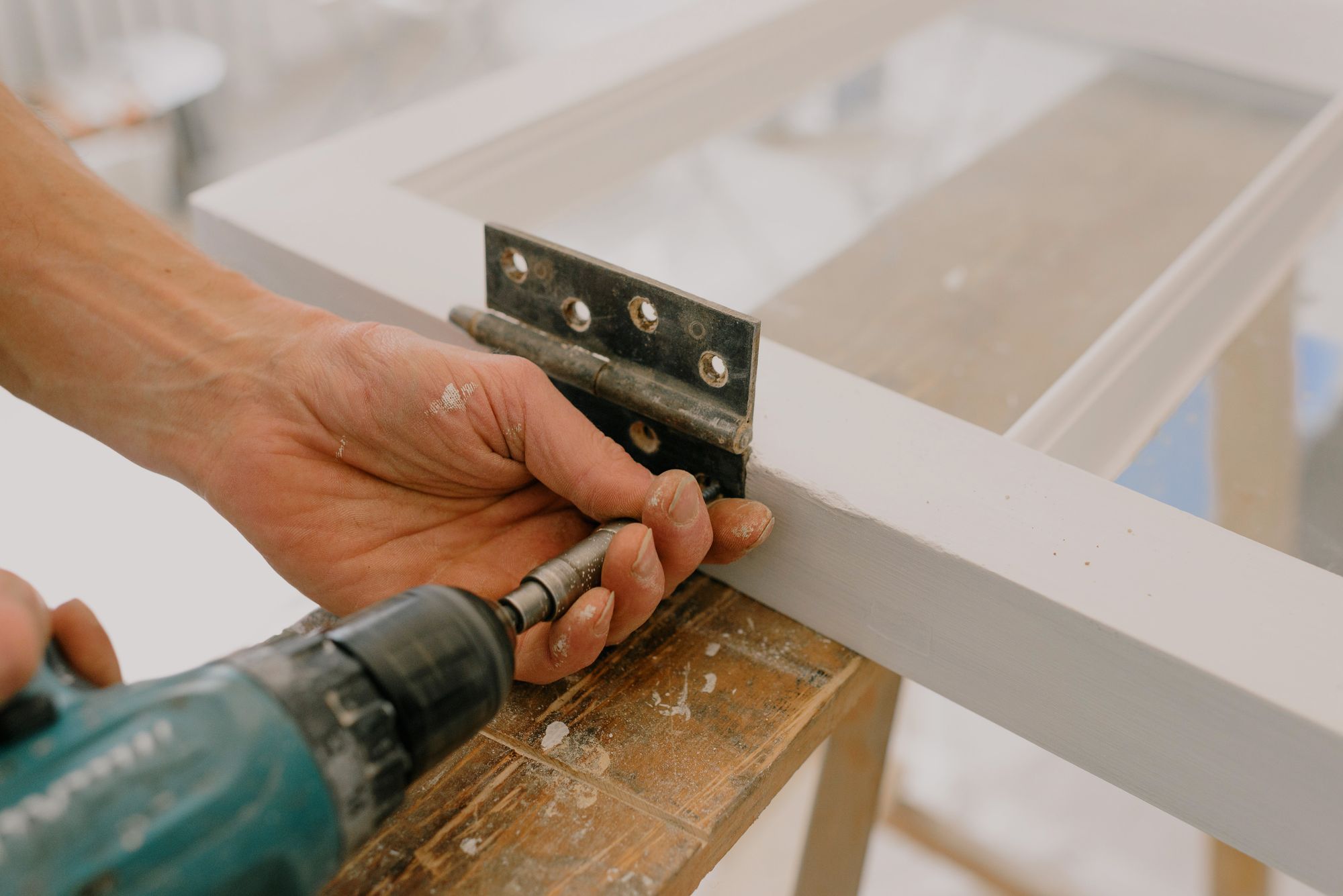 Stock photo of hands drilling a hinge into a door frame