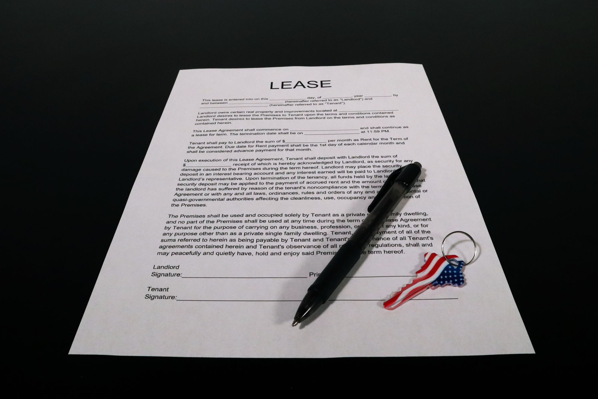 A printed lease agreement on a table with a pen and a door key