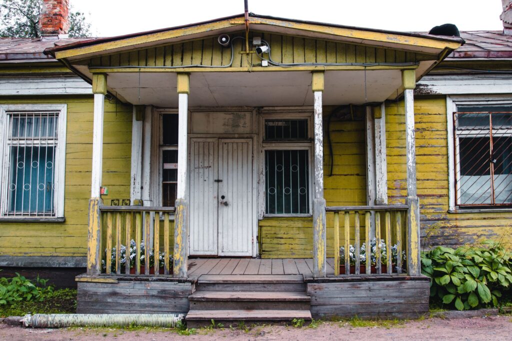 Stock photo of an old yellow house with a covered front porch and steps