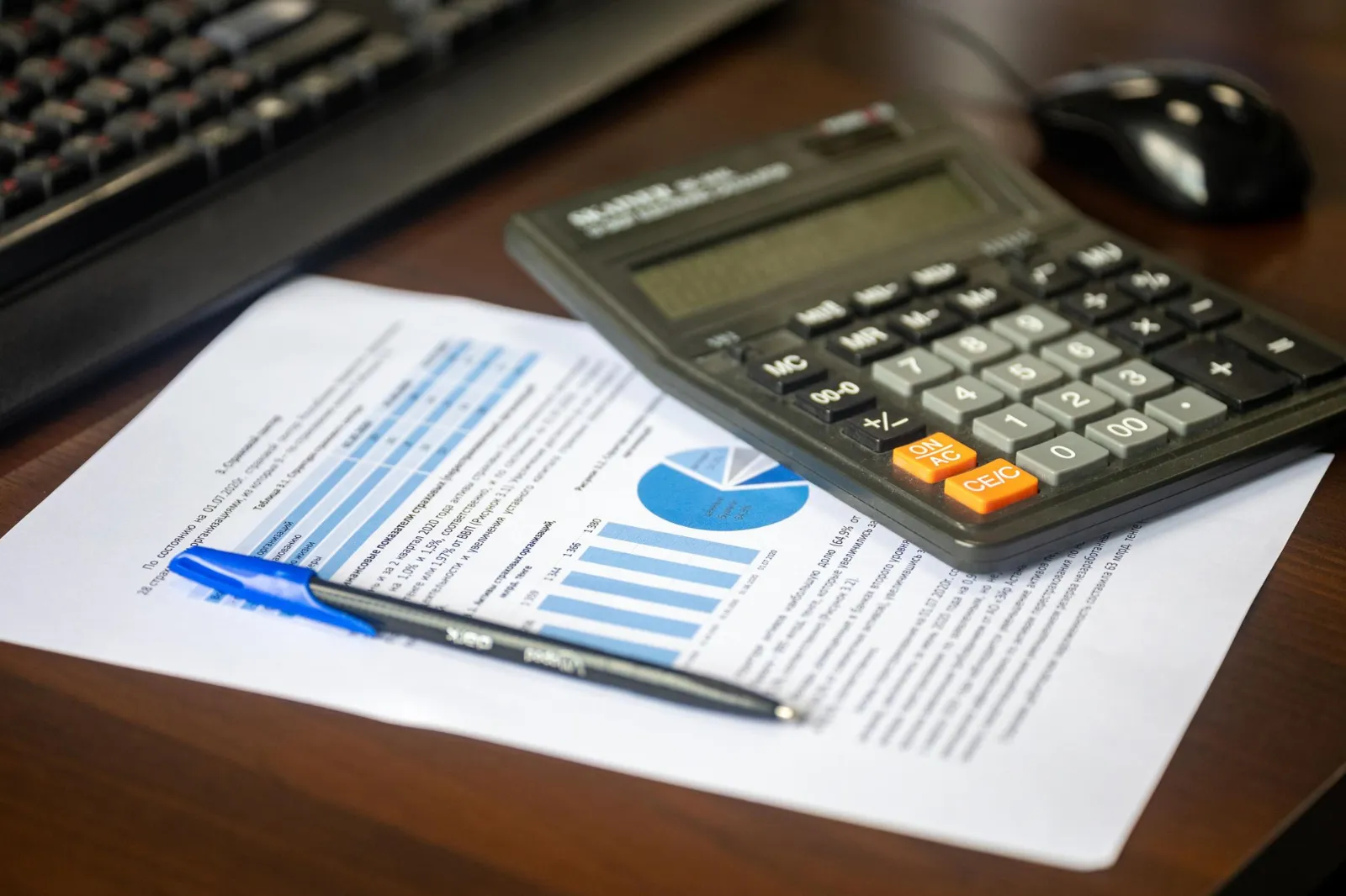 A calculator on a printed financial report with a pen
