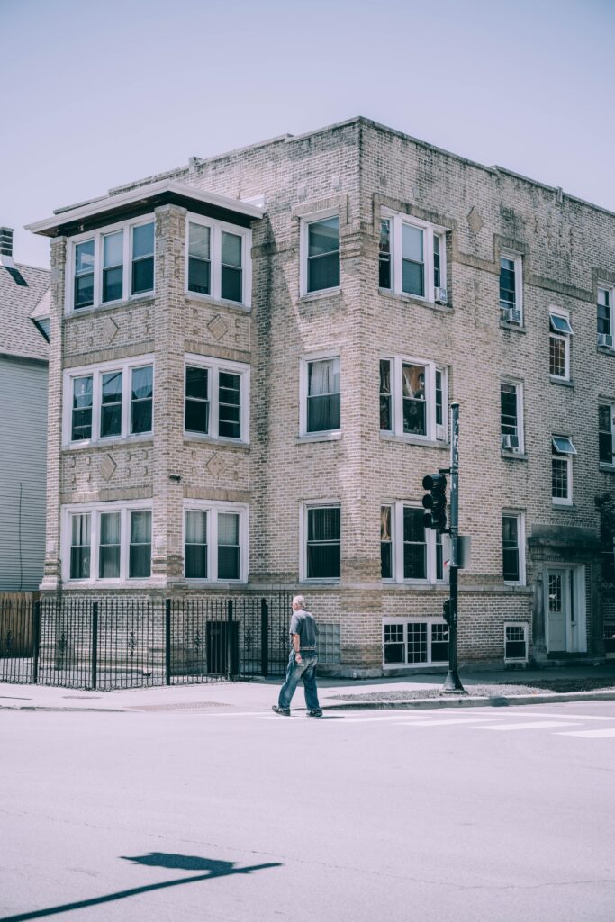 Man crossing a Chicago street beside a classic brick apartment building
