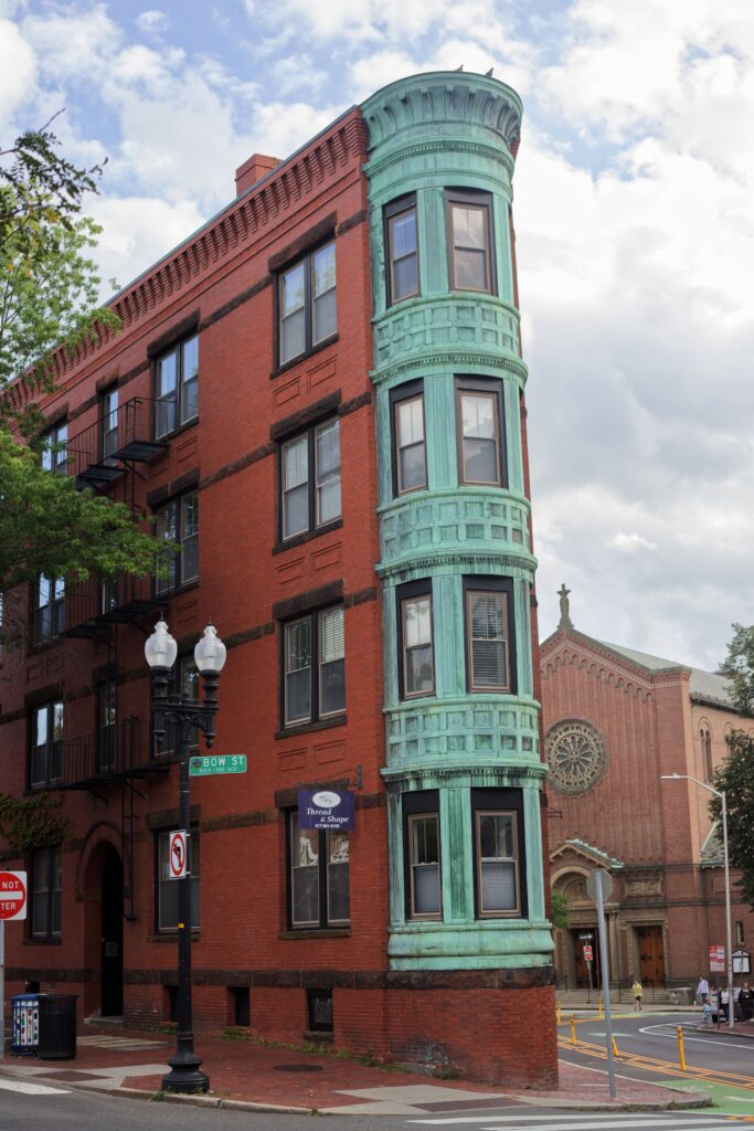 Red brick multi-family house with turquoise-painted trim in Cambridge, Massachusetts