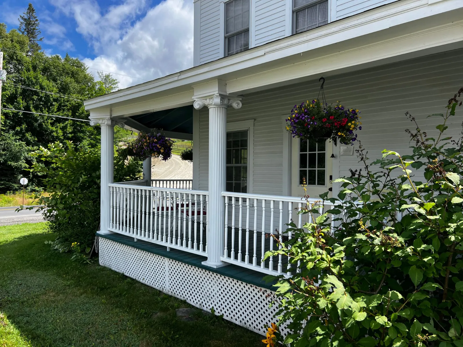 A front porch with white columns and hanging flower baskets