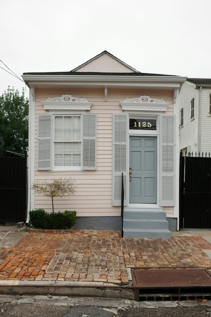 Small pink house with grey shutters and a front porch in Uptown New Orleans