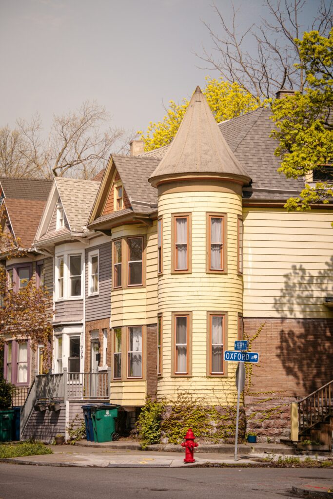 Yellow two-story house with a bay window and red fire hydrant in Buffalo, New York