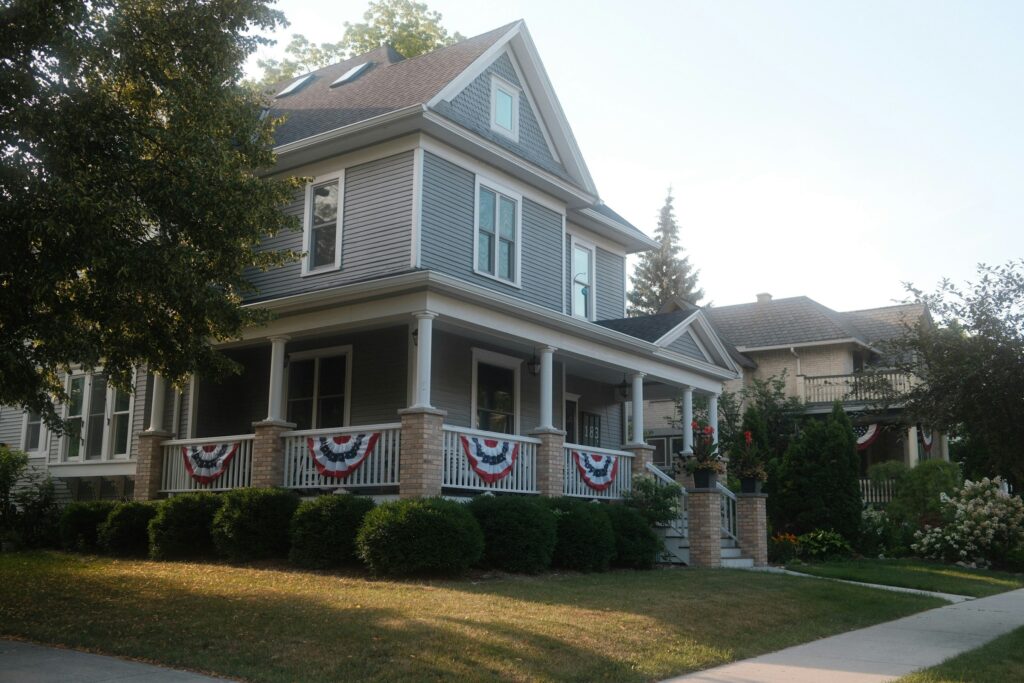 Gray two-story house with a deep front porch and red, white and blue bunting