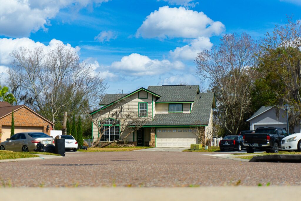 Suburban street lined with blue, green and purple houses with garages and parked cars
