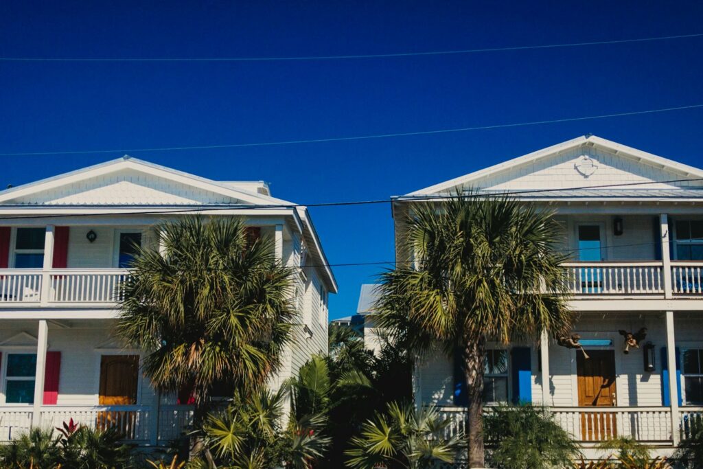 Two white two-story houses with front galleries and palms in Key West, Florida