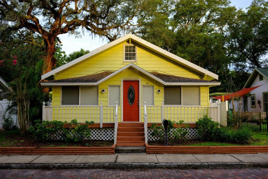 Yellow wooden bungalow with a front porch under live oaks in Safety Harbor, Florida
