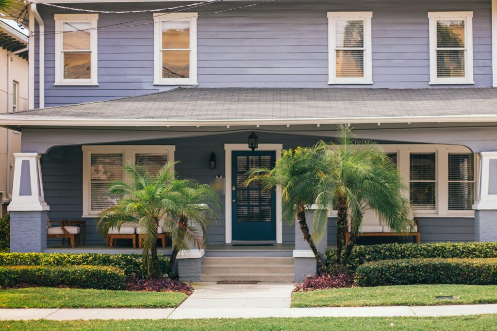 Two-story blue house with a deep front porch and palms in the Tampa Bay area, Florida