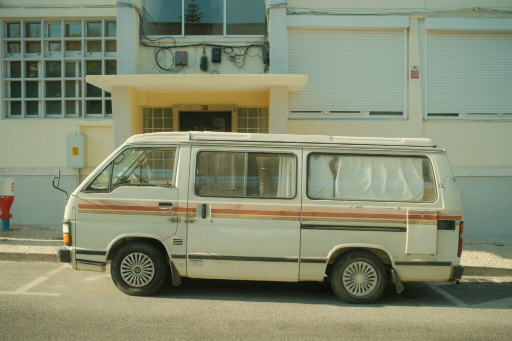 An older white van with orange stripes parked on a city street
