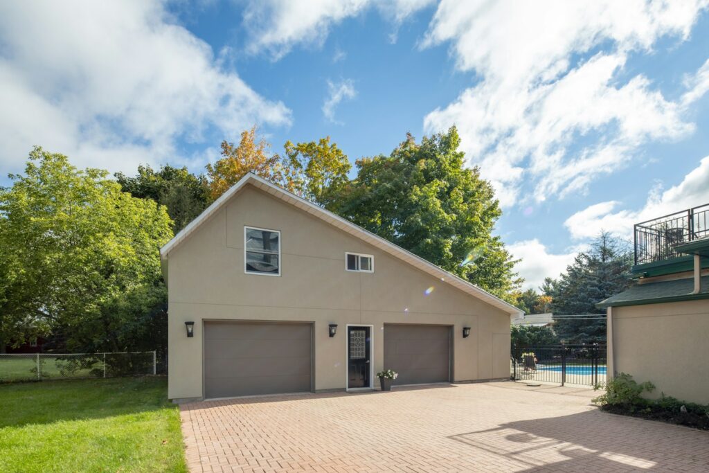 A detached two-car garage with a second floor above it, beside a house