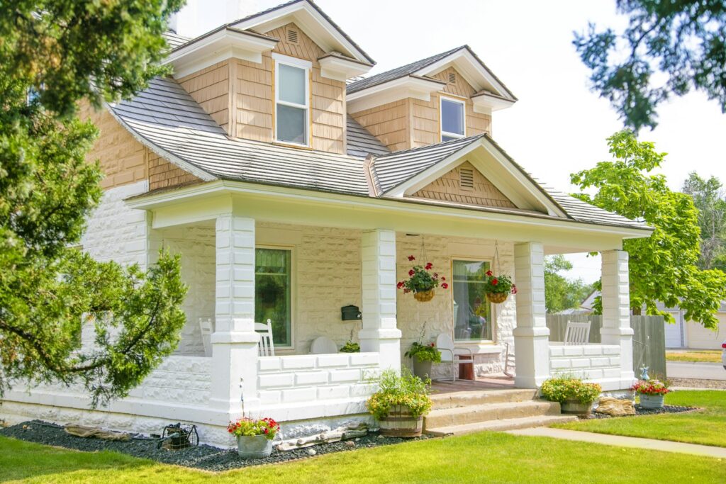 A two-story house with a wide covered front porch on a sunny street